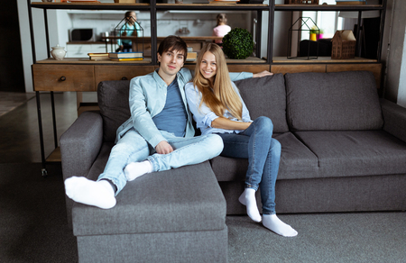 Full size portrait of attractive trendy couple sitting in modern open space apartmentの写真素材