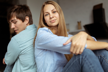 Young lovely couple sitting on the table back to backの写真素材