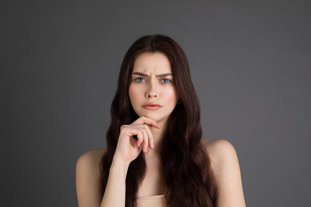 Close up portrait of stylish teenage girl with dark long hair touching chinの写真素材