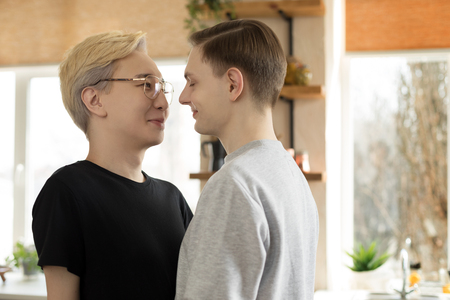 Close up portrait of two young international gay men in casual clothes, one asian blonde men in eyeglasses, seon european with brown hairの写真素材