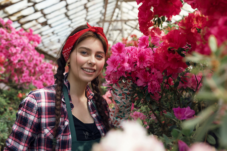 Spring and summer flowers. Happy woman gardener in work clothes looking at the cameraの写真素材