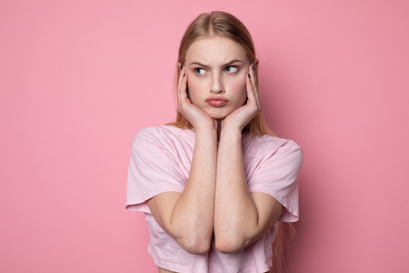 Close up portrait of young beautiful stressed angry girl holding hands on faceの写真素材