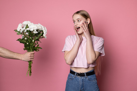 Happy beautiful young female with blonde hair surprised by the flowers that gave her boyfriendの写真素材