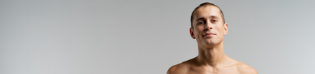 Cropped portrait of young man with short haircut, looking at the camera, isolated over grey background, copyspace for your textの写真素材