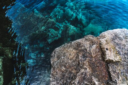 Mountain lake, clear turquoise water and big rock
