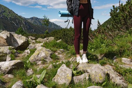 Girl in red sports pants standing with backpack among the mountainsの写真素材