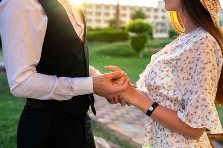 Young lovely couple in elegant clothes standing opposite each other and holding hamds togetherの写真素材