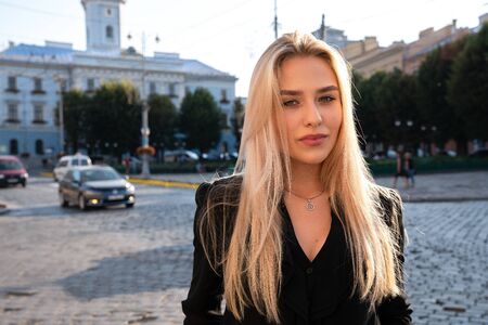 Chernivtsi, Ukraine, 25.08.2019: Beautiful seriously blonde young woman in black dress standing among street of old cityのeditorial素材