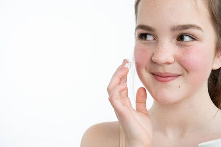 Beautiful young woman with cosmetic face cream. Photo close-up on a white backgroundの写真素材