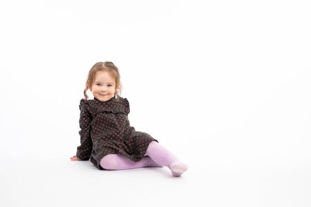 Funny redhead girl in purple tights sitting on the floor and looking at the camera isolated over white backgroundの写真素材