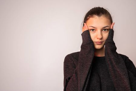 Depressed, sad female in gbalck shirt holds her hands on her face and looking at the camera isolated...