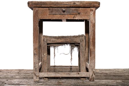 Shabby old vintage shoemaker's table and chair stands on the wooden floor, isolated over white...