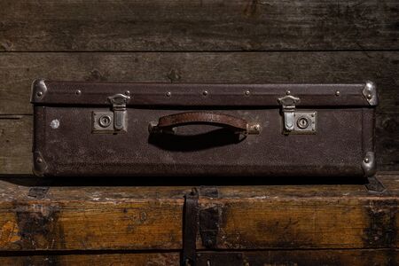 Old suitcases against wooden wall background or texture