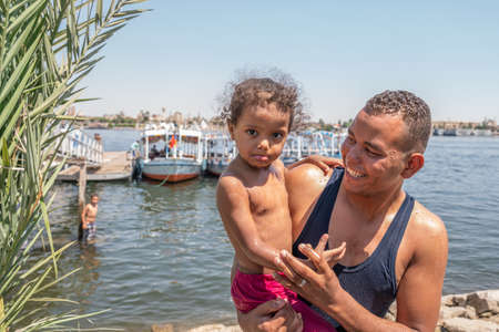 Luxor, Egypt - 29.03.2020: Smiling and happy father and his daughter playing on the beach. Concept of friendly family. International water day, 22 marchのeditorial素材