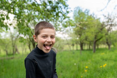 Happy little boy in black shirt shows tongue to the cameraの写真素材
