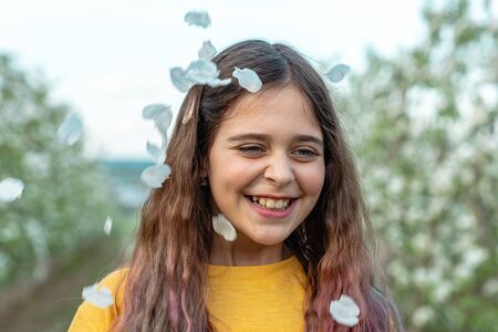 Happy smiling brunette girl under white falling petalsの写真素材