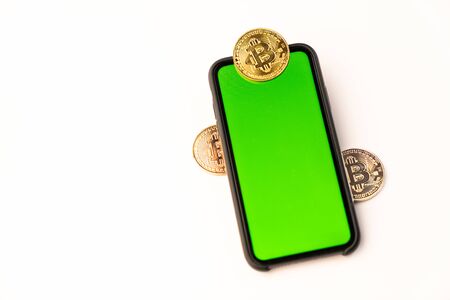 Bitcoin golden coins on handphone with green screen isolated on white backgroundの写真素材