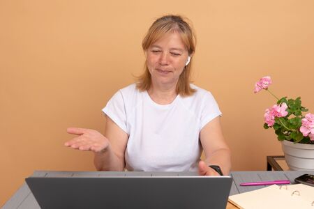Portrait of happy senior woman in wireless headphones who looking at laptop screen at home....