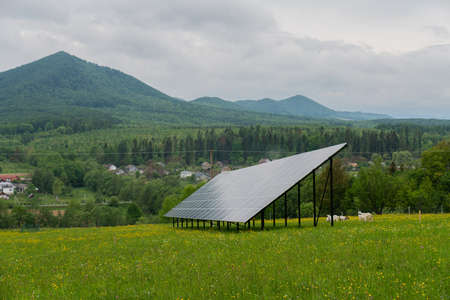 Solar panels against mountain landscape against blue sky with clouds