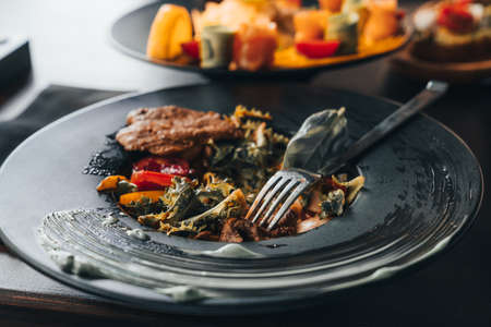 Fresh salad with chicken, tomato and greens spinach, arugula on black plate with fork. Healthy food