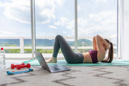 Exercises abs. Sporty girl in black sportswear doing abc exercises indoorsの写真素材