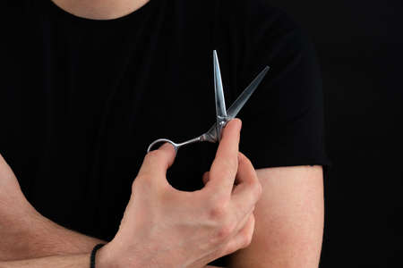 Cropped photo of a barber having his arms crossed, holding equipments in handの写真素材