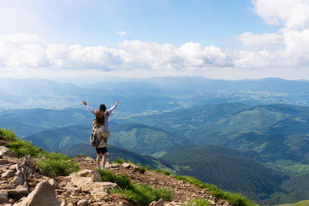 Hikers relaxing on top of a mountain and enjoying the view of valley