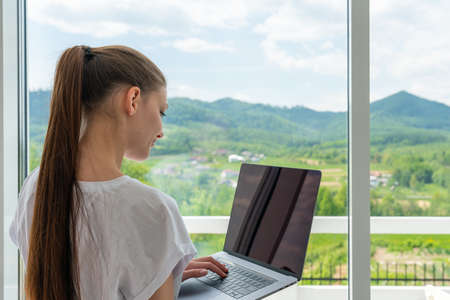 Cute smiling woman using laptop at home. Student girl working on computerの写真素材