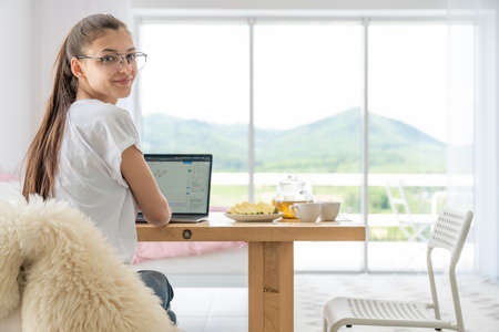 Cheerful woman using laptop at home. Young girl working on computer. Blogger, writer, journalist or...