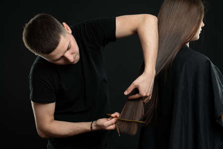 Side view of hairstylist doing hairstyle to stylish modelの写真素材