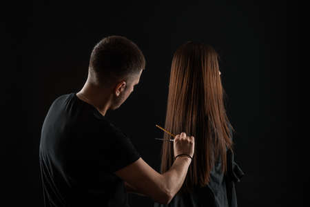 Beautiful young hairdresser doing hairstyle to female client in beauty salonの写真素材