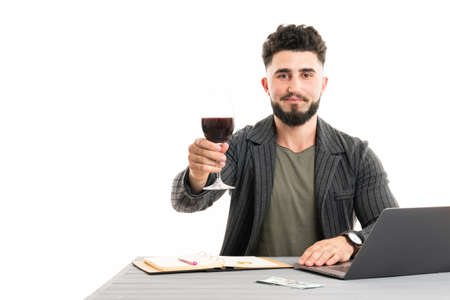 Businessman getting a glass of wine and using laptopの写真素材