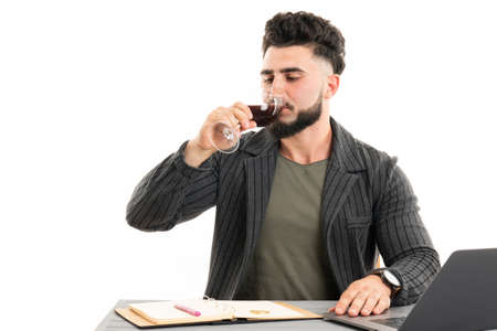 Handsome businessman dressed in the suit drinking red wine sittingの写真素材