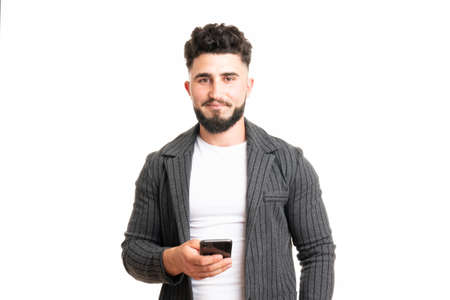 Positive European American male with smile, holds modern cell phone, types text message and feedback, surfes social networks, rejoices high speed interent connectionの写真素材