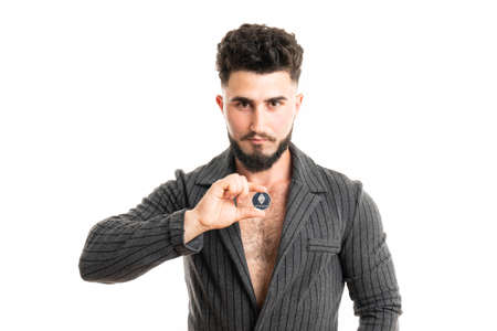 Businessman in gray suit is holding silver ethereum coin between fingers, smart contract crypto currency sign, isolated white backgroundの写真素材