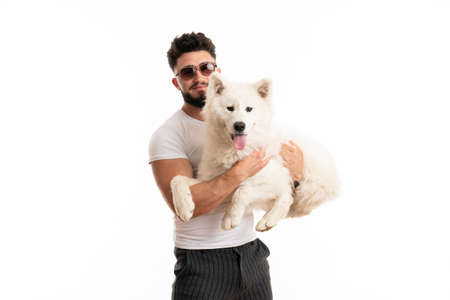Pleased man in glasses holds samoyed dog in his hands