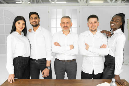 Group picture of happy diverse multiethnic young businesspeople in white shirts posing together at workplace in officeの写真素材