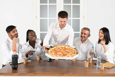 Lunch break. Young employees ordered pizza to the office and have lunch together in their officeの写真素材