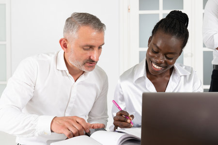 Two business partners, young African woman and senior Caucasian man, working with new ideas about project in conferenceの写真素材