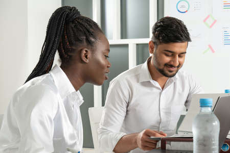 Multiethnic boss and secretary or assistant work as team. Ask colleague for opinion. Office business...