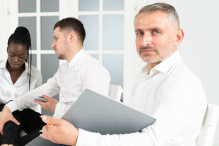 Portrait of confident male entrepreneur holding modern touch pad in hands and looking at camera during work day in company officeの写真素材
