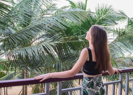 a girl brunette on a balcony near the palm treesの写真素材