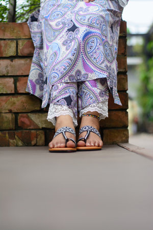 Closeup of woman's feet wearing sandals sitting on brick wall