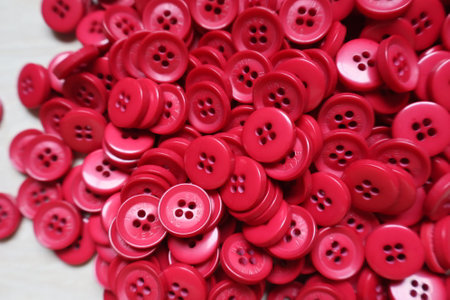 Red sewing buttons on white wooden background. Top view. Selective focus.