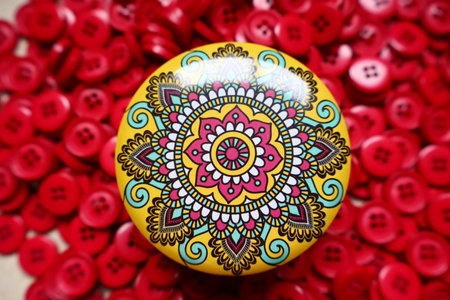 Relaxing and easy mandala design on a yellow pot with red sewing button at background.の写真素材