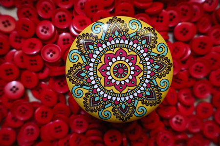 Relaxing and easy mandala design on a yellow pot with red sewing button at background.の写真素材