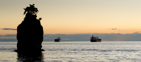 Siwash Rock, on the edge of Stanley Park, Vancouver, is seen silhoutted against the yellow evening...