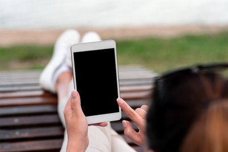 Top view mockup image of woman s hands holding and using black tablet pc with blank white desktop...