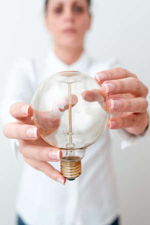 Lady Holding Lamp With Formal Outfit Presenting New Ideas For Project, Business Woman Showing Bulb With Two Hands Exhibiting New Technologies, Lightbulb Presenting Another Openionの写真素材