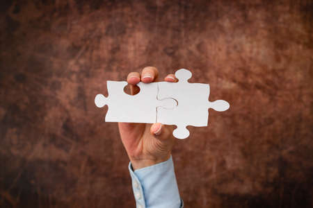 Hands Holding Two Pieces Of Jigsaw Puzzle.Cooperation For Finding And Resolving Missing Ideas At Work.Businessman Find Strategy For Resolving, Connecting Thoughtsの写真素材